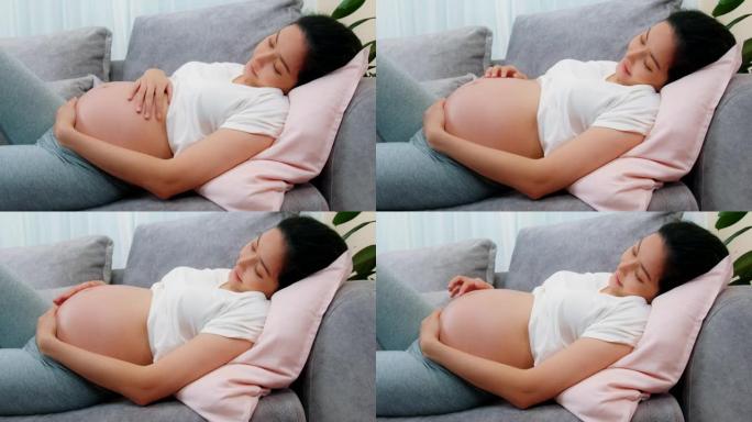 孕妇坐在沙发上，双手放在腹部的特写镜头