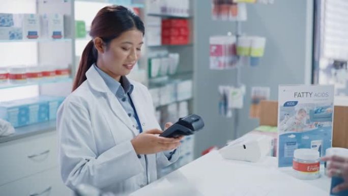 药房药房收银台: 专业的亚洲女药剂师销售药包，解释如何使用，客户使用非接触式支付终端和信用卡付款