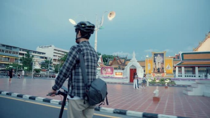 旅行者男子骑着电动滑板车绕着巨大的秋千