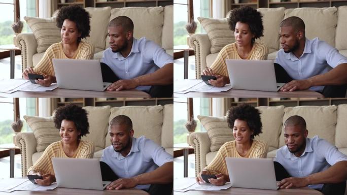 美国黑人配偶在家庭办公室用笔记本电脑计算账单