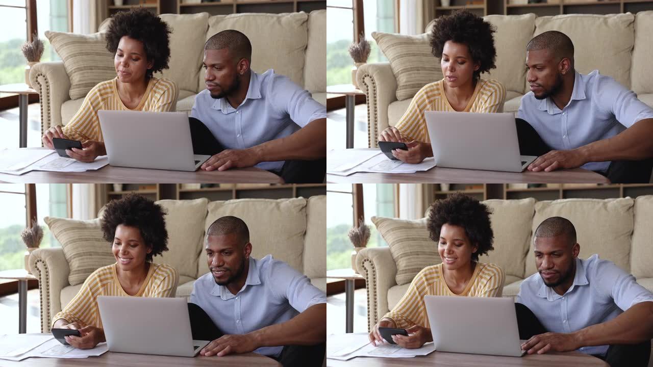 美国黑人配偶在家庭办公室用笔记本电脑计算账单