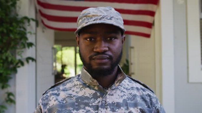 非裔美国男性士兵站在房子和美国国旗前的肖像