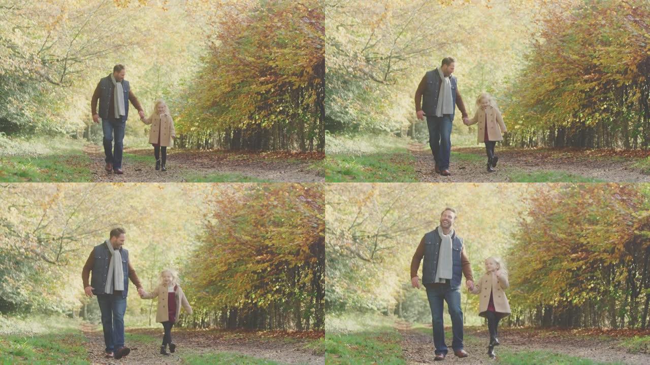 父亲和女儿牵着手，在秋天的乡村沿着赛道走，在家庭中跳跃