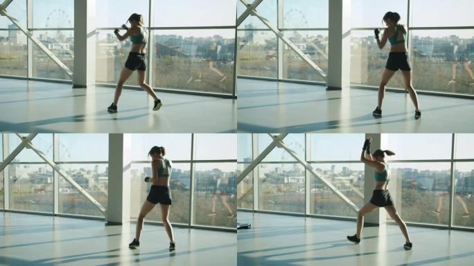 女性综合格斗选手在现代玻璃墙健身房训练拳打脚踢