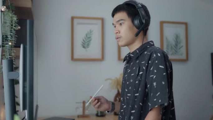 年轻的亚洲男子在家庭办公室通过电脑进行视频通话。