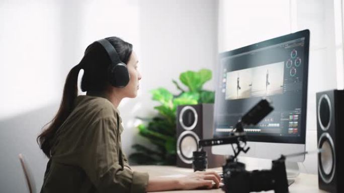 后期制作-女性视频编辑器在带耳机的计算机上进行视频编辑