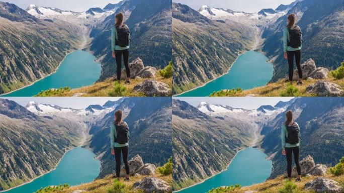 健康导向的女人站在山顶上，欣赏周围群山和绿松石湖的壮丽景色