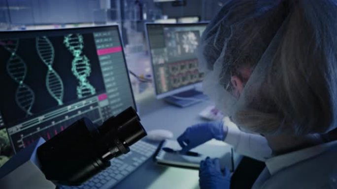 在实验室设备上工作的女人。计算机屏幕上的DNA研究