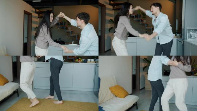 幸福的年轻夫妇的慢动作在家里的厨房里跳舞表达爱