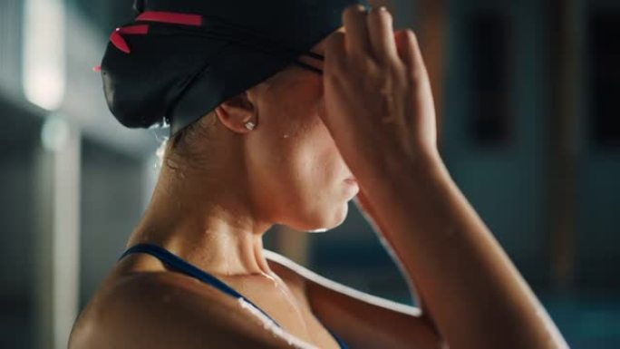美丽的职业女子游泳运动员在游泳池里，戴着帽子，自信地看着前方，戴上眼镜，准备夺冠，创造了新的世界纪录