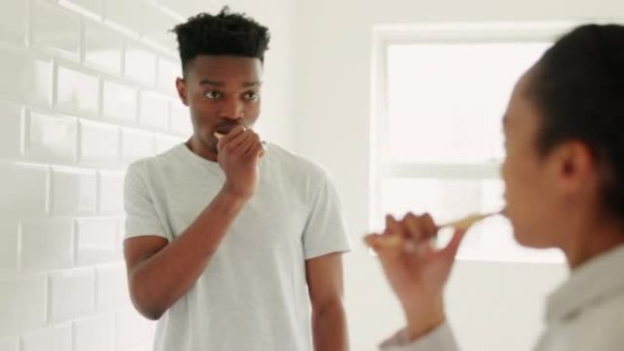 年轻黑人夫妇的牙齿保健，在浴室用牙刷刷牙，在家随意交谈。清洁口腔个人卫生，男女一起聊天的早晨常规