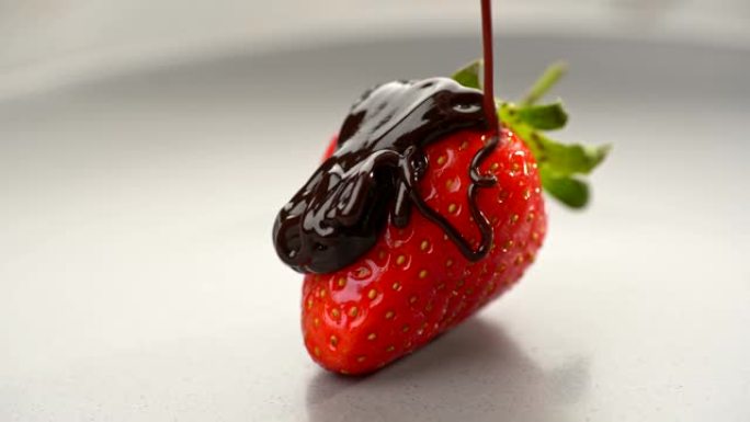 健康的时令食品。鲜红色美味的甜草莓倒入液体巧克力。隔离在灰色板上。滑块镜头，4K