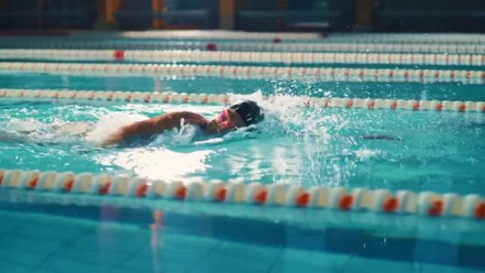 成功的女子游泳运动员赛车，在游泳池游泳。职业运动员决心使用前爬行自由泳赢得冠军。彩色电影镜头。侧视图