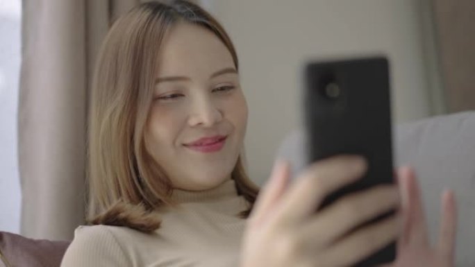 年轻的亚洲女性在家中放松身心时使用智能手机进行在线购物