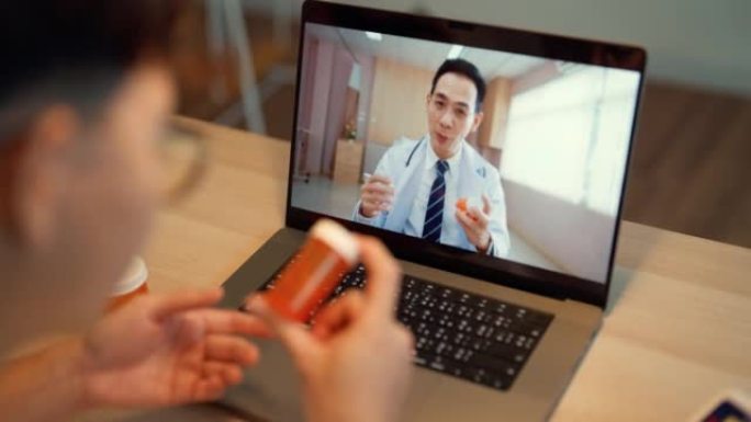 年轻的亚洲男子与医生进行视频远程医疗通话。