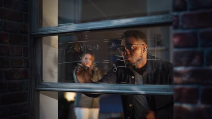 黑人年轻人通过使用可擦除的玻璃标记在家里的窗户上向女性朋友解释数学方程式。两名多民族大学生和室友准备