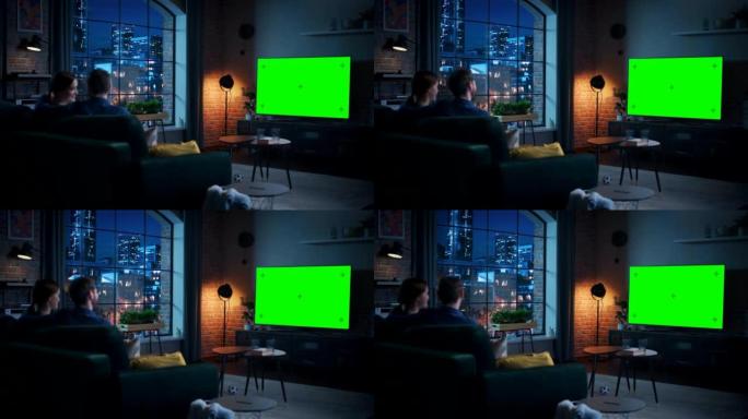 年轻的夫妇花时间在家里，坐在沙发上，在他们时尚的阁楼公寓里看绿屏模拟显示的电视。男人和女人流晚间电影