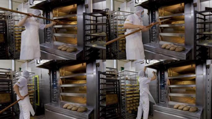 在食品加工厂工作的成年男子从烤箱中取出新鲜裸露的面包