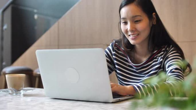 亚洲女性在咖啡馆使用笔记本电脑