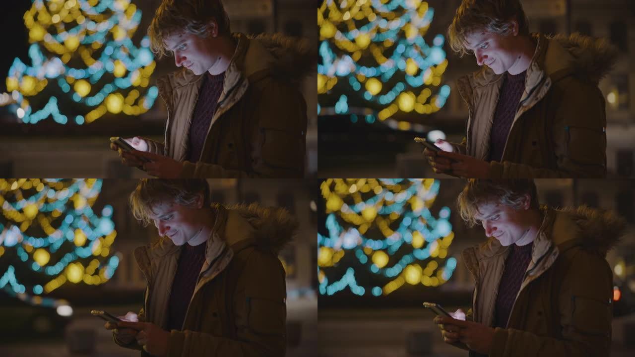 WS年轻人在城镇广场上使用他的智能手机，背景是圣诞树