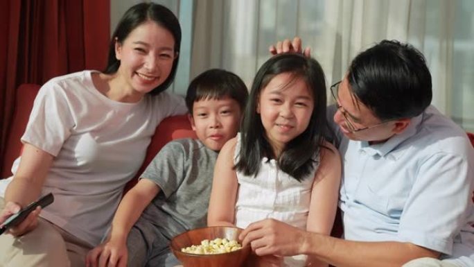 一个温暖的家庭，父亲，母亲，儿子，女儿一起用相机作为电视屏幕看电视。它代表了整个家庭幸福地在一起度过