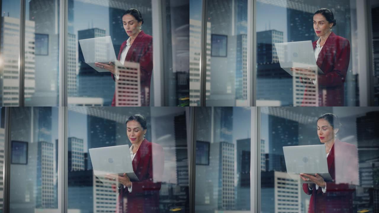 时尚女商人使用笔记本电脑的肖像，看着窗外的城市。成功的女首席执行官在计算机上工作，谈判购买在线购物电
