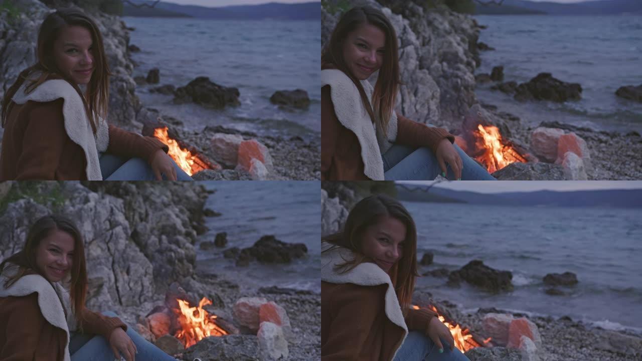 晚上坐在篝火旁的年轻女子的肖像