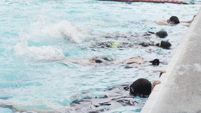 亚洲中国游泳运动员在游泳教练的指导下在游泳池边练习腿部泼水