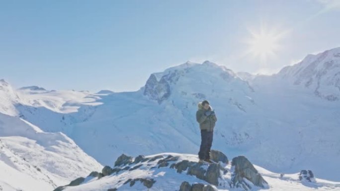 Man操作具有马特宏峰日落背景的无人机遥控器。瑞士阿尔卑斯山。