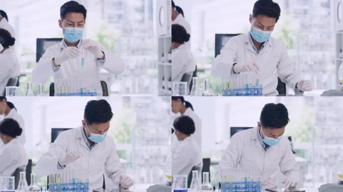 年轻的男性生物学家在COVID研究实验室将试管结果输入数字平板电脑。戴着口罩的科学家或化学专家，在临