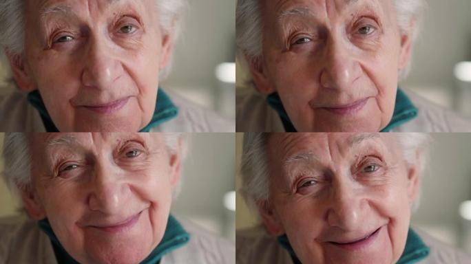 微笑的真实电影特写镜头退休的残疾白发老年妇女坐在轮椅上在家里的相机里微笑。生活观念，家庭，对老年人的