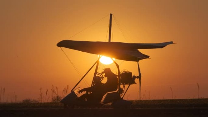 在美丽的日落背景下通过悬挂式滑翔机进行飞行测试的准备