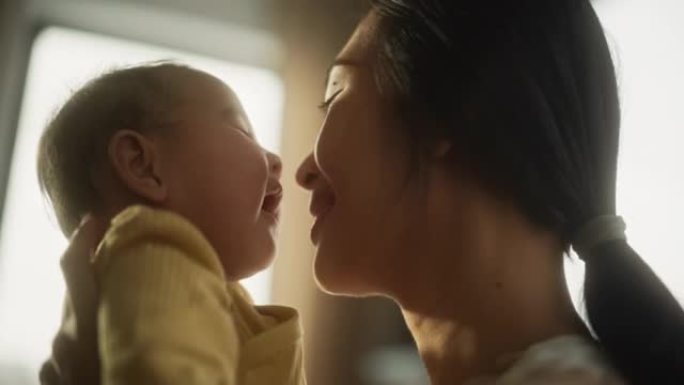 母爱概念: 一个可爱的亚洲婴儿的特写肖像，笑着享受与母亲的亲密时光，用爱看着她。与婴儿有特殊时刻的母