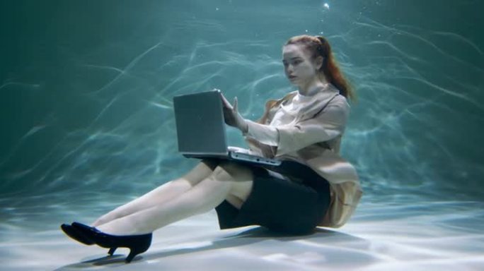 抽象过劳概念。穿着办公套装的漂亮年轻女商人用笔记本电脑在水下慢动作下工作。