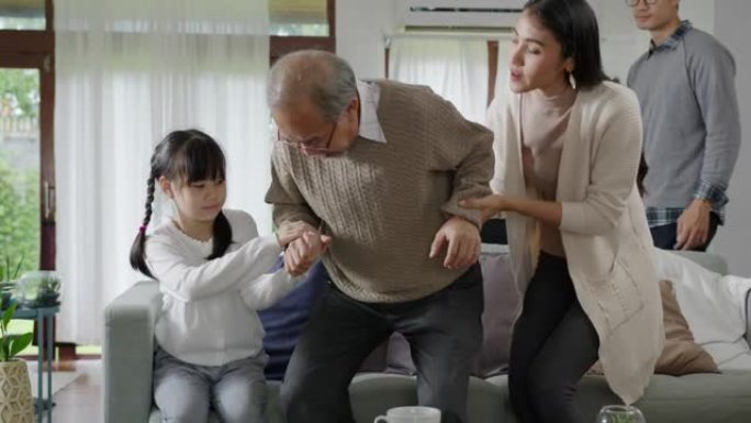 亚洲老年男爷爷坐在家中客厅的沙发沙发上进行隔离概念保健，有慢性健康问题或腰痛的退休老人与家人一起。