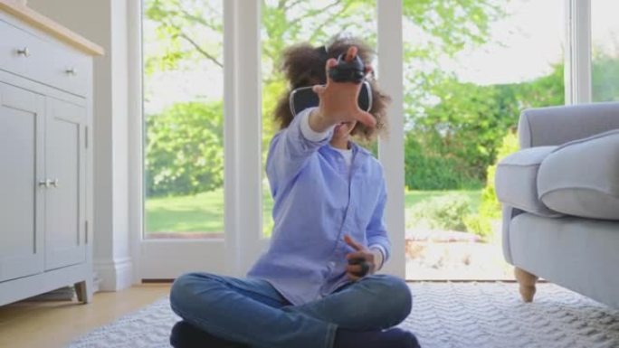 男孩坐在家里的地板上戴着VR耳机玩驾驶电脑游戏-慢动作拍摄