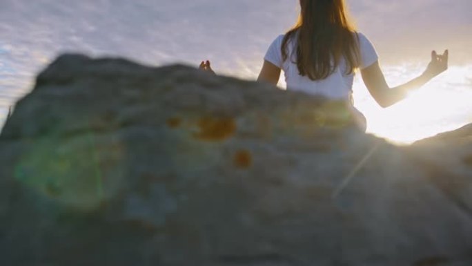 女人在悬崖上做瑜伽的后视图