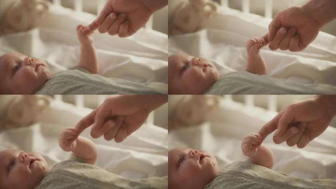 特写婴儿躺在婴儿床的背部时，用母亲的手和手指玩耍的镜头。高加索新生儿蹒跚学步的孩子和妈妈在一起。童年
