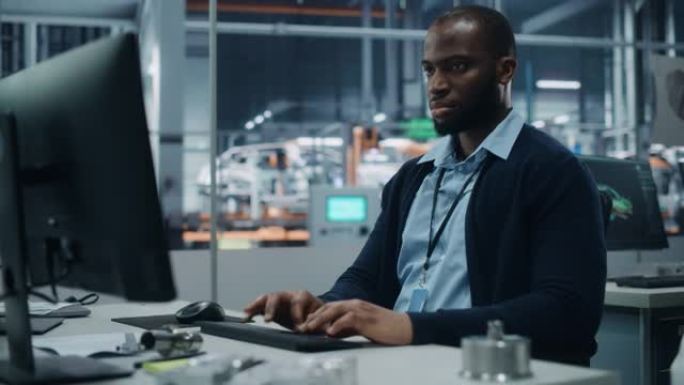 汽车厂办公室: 自信的黑人男总工程师在台式电脑上工作的肖像。自动化机器人手臂装配线制造高科技电动汽车