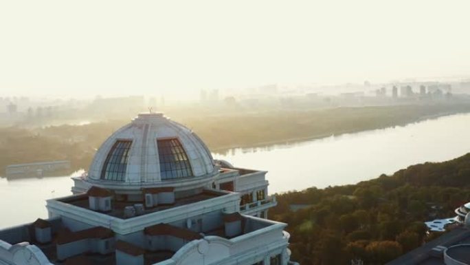 无人机在乌克兰基辅的白色建筑留下，沿着日出第聂伯河大桥全景的壮丽宁静景色飞行。