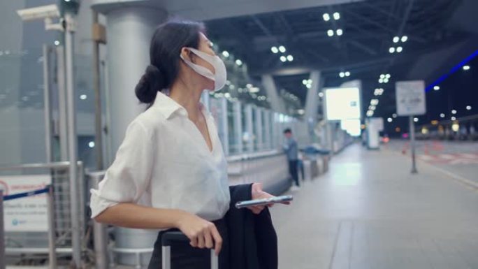亚洲商务女孩到达目的地戴口罩站在外面看智能手机候车机在国内机场。