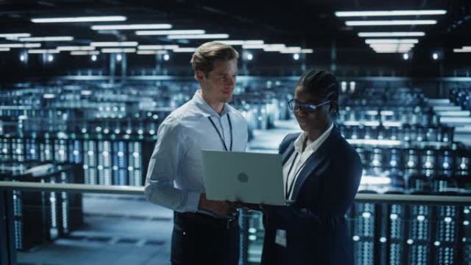 数据中心女系统管理员和男IT专家交谈，使用笔记本电脑。信息技术工程师在云计算服务器场中从事网络安全网
