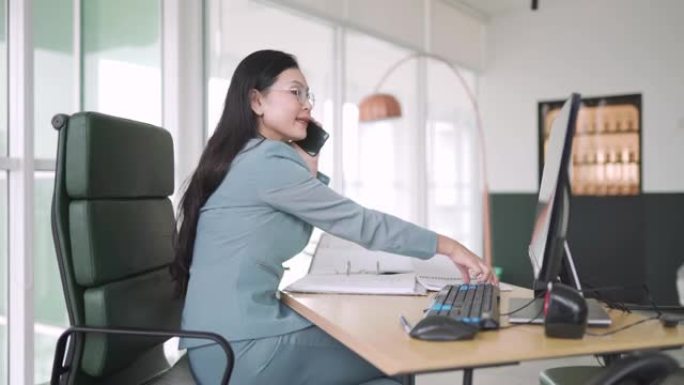 亚洲华裔女性行政管理人员坐在她的办公室在台式电脑前工作