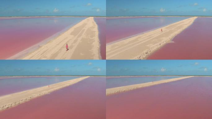 空中: 无人机拍摄的一名妇女探索尤卡坦半岛充满活力的粉红盐农场。