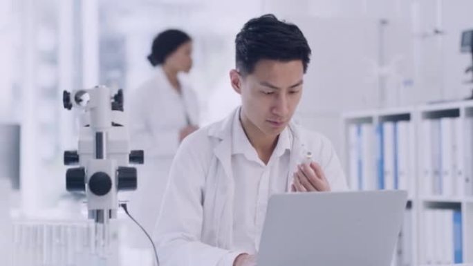 科学家在实验室里用笔记本电脑分析试管样品。男性病理学家一边在线评估数据一边进行法医研究。临床研究者记