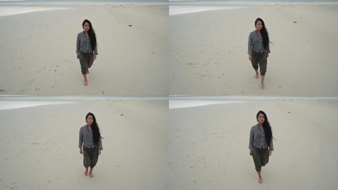 沉思的女人在沙滩上行走