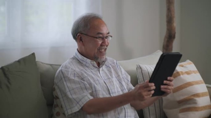 老人使用数字平板电脑并在家中进行视频通话