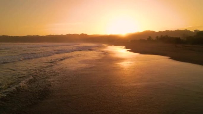 空中: 海浪在金色的光线下洒在热带沙滩上