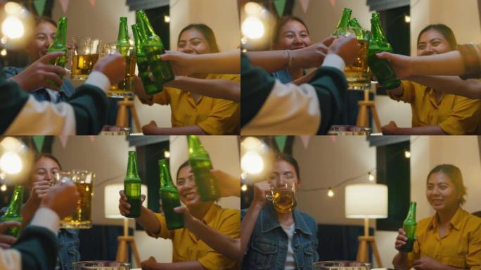 一群多民族的亚洲年轻朋友喝酒精啤酒瓶玻璃，开心地笑，在夜生活室内享受聚会。