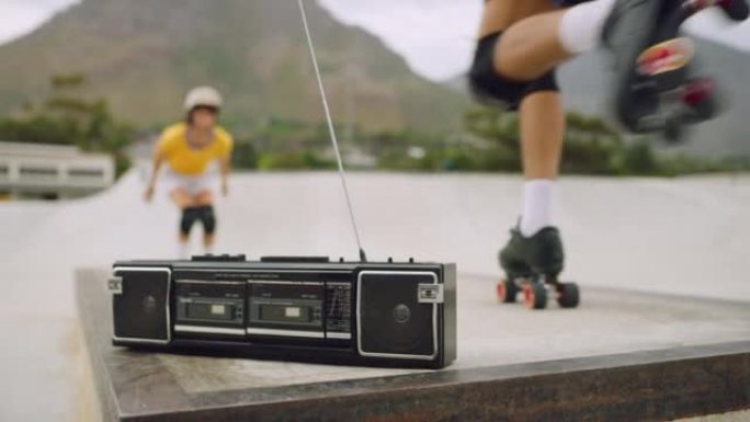 复古收音机的特写镜头，以冷却城市溜冰者练习他们的技能。年轻有趣的女rollerbladers在外面的